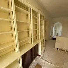 Yellow bookshelves line a narrow hallway with a sheet-covered floor