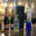 A bottle of vodka, a bottle of champagne, and another bottle of vodka arranged on a table.