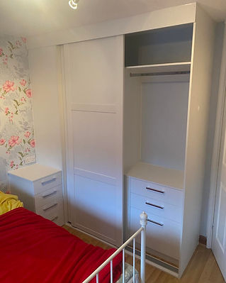 A bedroom features a white wardrobe with open shelving and drawers