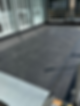 A flat rooftop covered with dark waterproof material