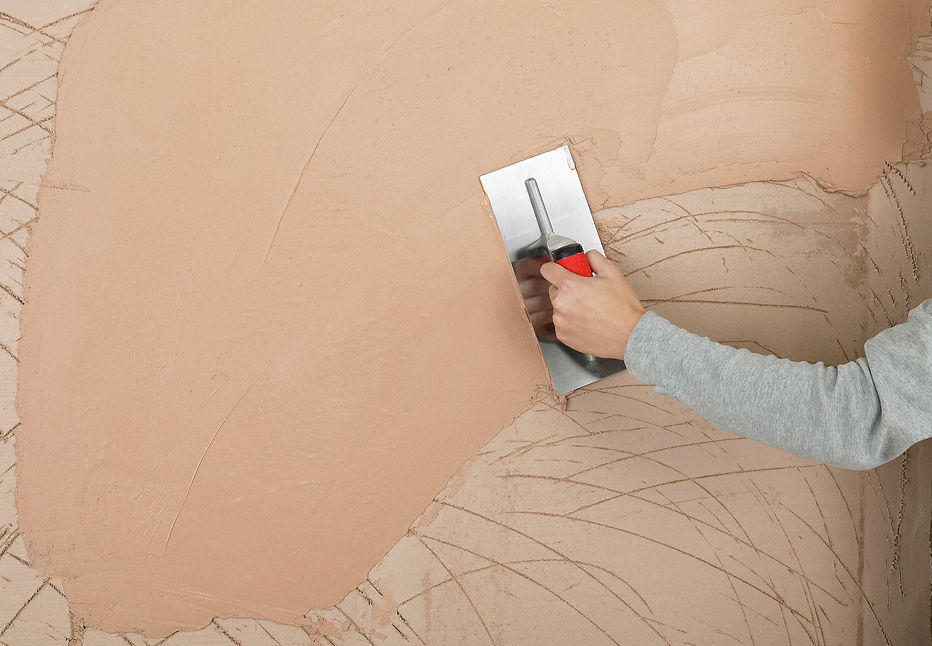 close-up image of a worker's hand while using plastering trowel