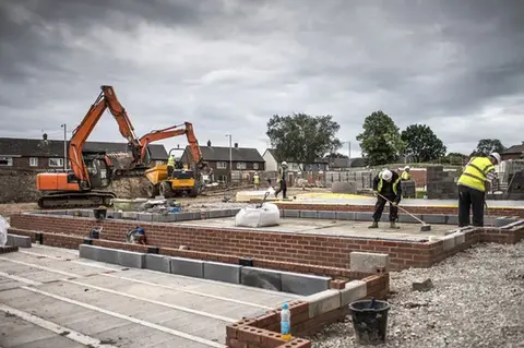 Workers constructing a brick house.