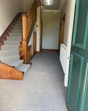 A hallway with a wooden staircase on the left, leading up.
