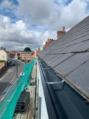house roof with scaffolding and black gutter system