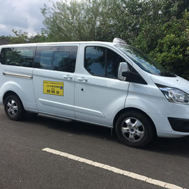 A white cab parked in front of a tree on the road