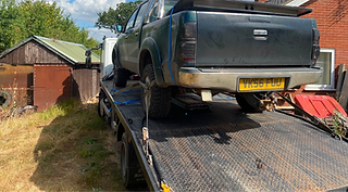 A flatbed truck transporting another truck securely on its rear