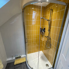 glass shower area with yellow tiles in a bathroom