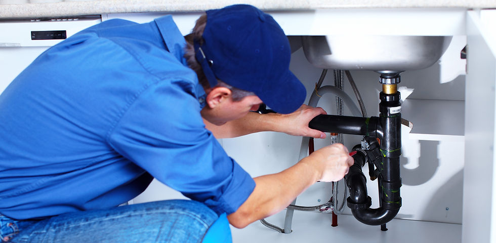 Plumber sitting under a bathroom sink to fix the drain pipe