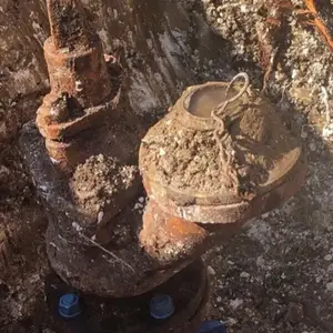 A rusty and muddy pipe in the ground