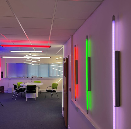 Modern office space with neon wall lights in red, green, and purple, and a white round tab