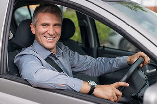 smiling man driving a silver car
