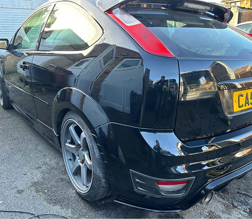 A shiny black hatchback car shown from the rear side.