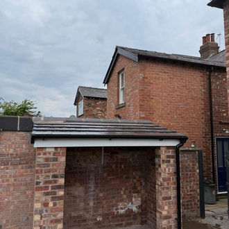 A brick garage featuring a sloped roof