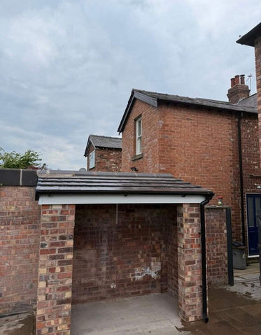 A brick garage featuring a sloped roof