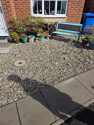 A small, pebbled garden with potted plants