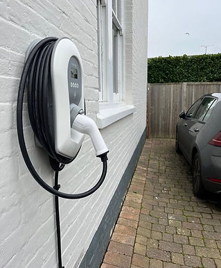 A white electric vehicle charging station is mounted on a brick wall