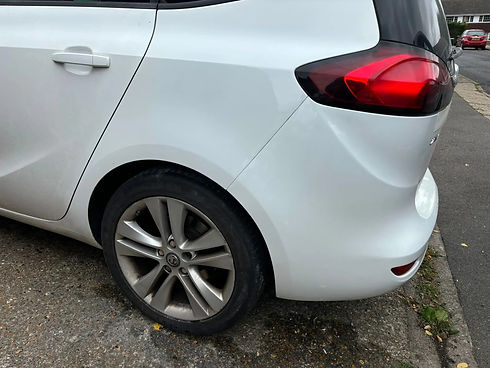 Close-up of a white car's rear section showing a red taillight