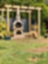 rustic wood-burning oven and a dog in a garden