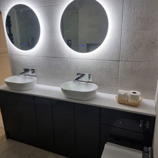 A modern bathroom features two illuminated round mirrors