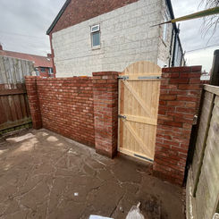 brick wall and wooden gate in front of a house