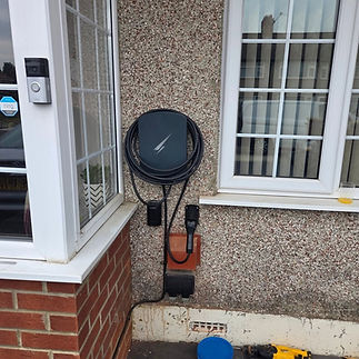 An electric vehicle charging station mounted on a pebble-dash house exterior