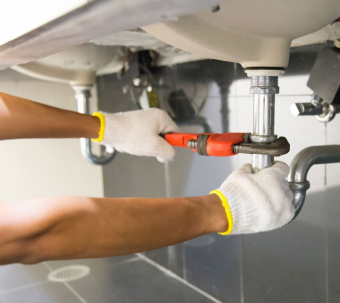plumber's hands while repairing sink pipe