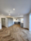 Spacious modern kitchen with herringbone wood flooring and white cabinets