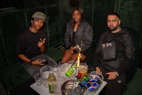 Three individuals seated on a couch, each holding a drink