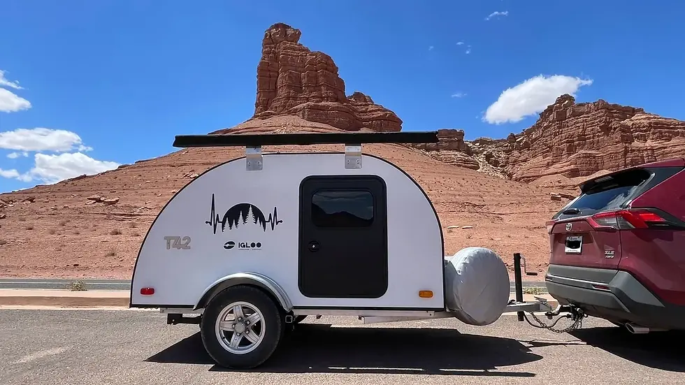 Igloo Caravane T42 teardrop trailer with awning, hitched to a compact SUV in a desert landscape