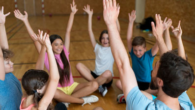 קבוצת ילדים במעגל עם ידיים מורמות בסדנת יוגה צחוק.