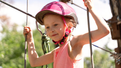 ילדה מטפסת על מתקני חבלים בפעילות אתגרית בטבע
