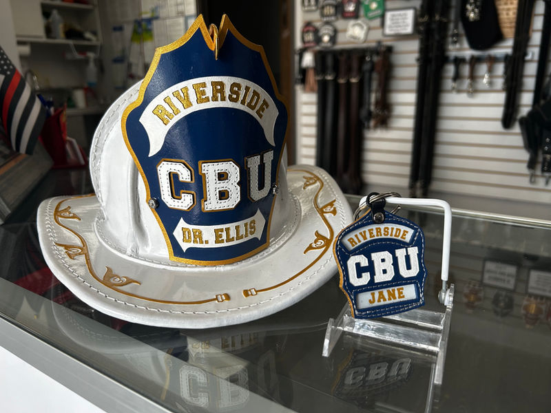 CBU Presentation Helmet with Gold Filigree and Shield Front with stitched in letters and a matching shield key fob next to it.
