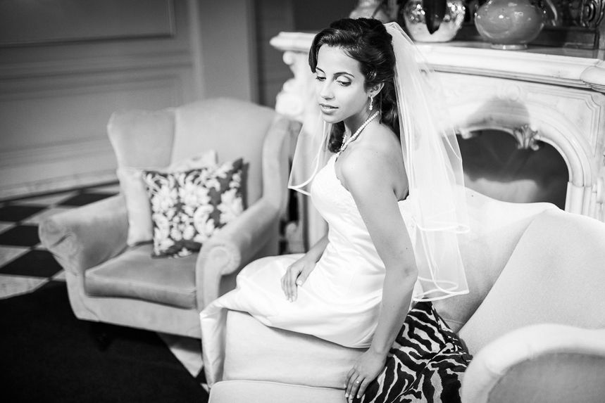 Junge Braut auf der Armlehne eines Sessels, ein Marmor-Kamin im Hintergrund