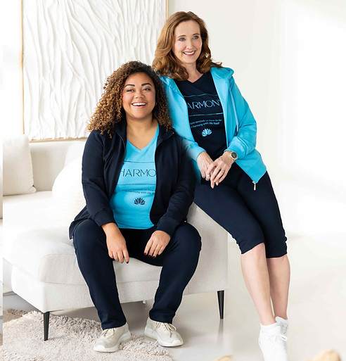 Slanke en curvy dame zitten ontspannen samen op de sofa in hun comfortabele Silvermedal damesjogging