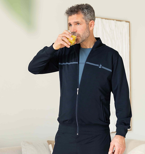 Heer in Silvermedal blauwe herenjogging drinkt met smaak gezond glas vers fruitsap