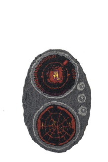 A grey oval with two vertical black circles with some red imagery inside. The top circle seems to have a nondescript symbol in the center while the bottom has red lines radiating from the center like a target or grid lines. In the grey background between and to the right side of the touching circles are three small circles that might show readings like fuel, speed, etc.