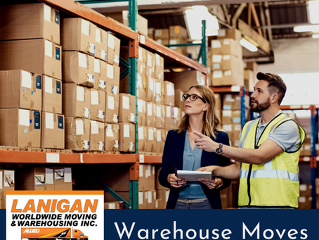 warehouse mover in yellow vest speaking with a manager holding a clip board in a warehouse - shelving is filled with boxes
