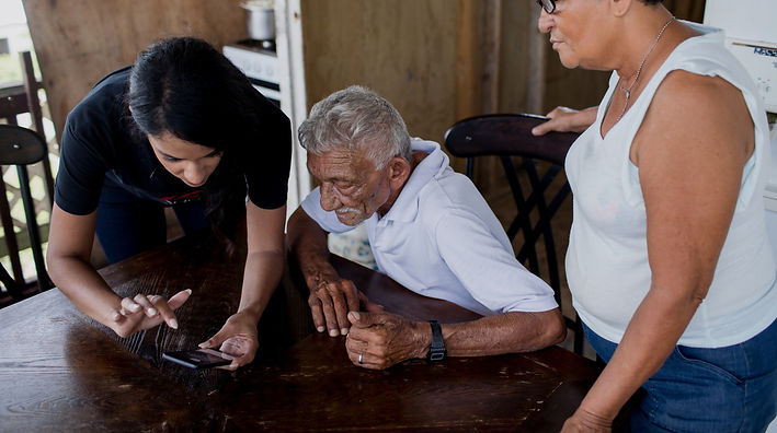 A senior looking at a phone with two people beside him.