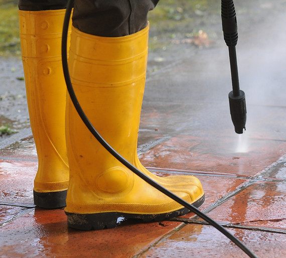 person-wearing-yellow-rubber-boots-with-high-pressure-water-nozzle-cleaning-dirt-tiles.jpg