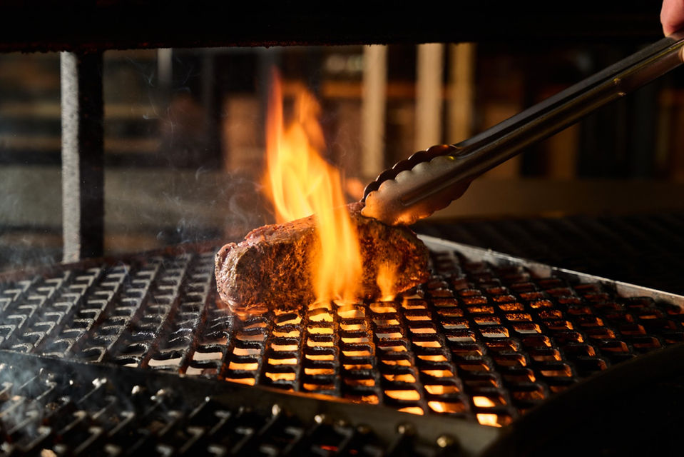 Prime steak being grilled over an open flame at Ascua
