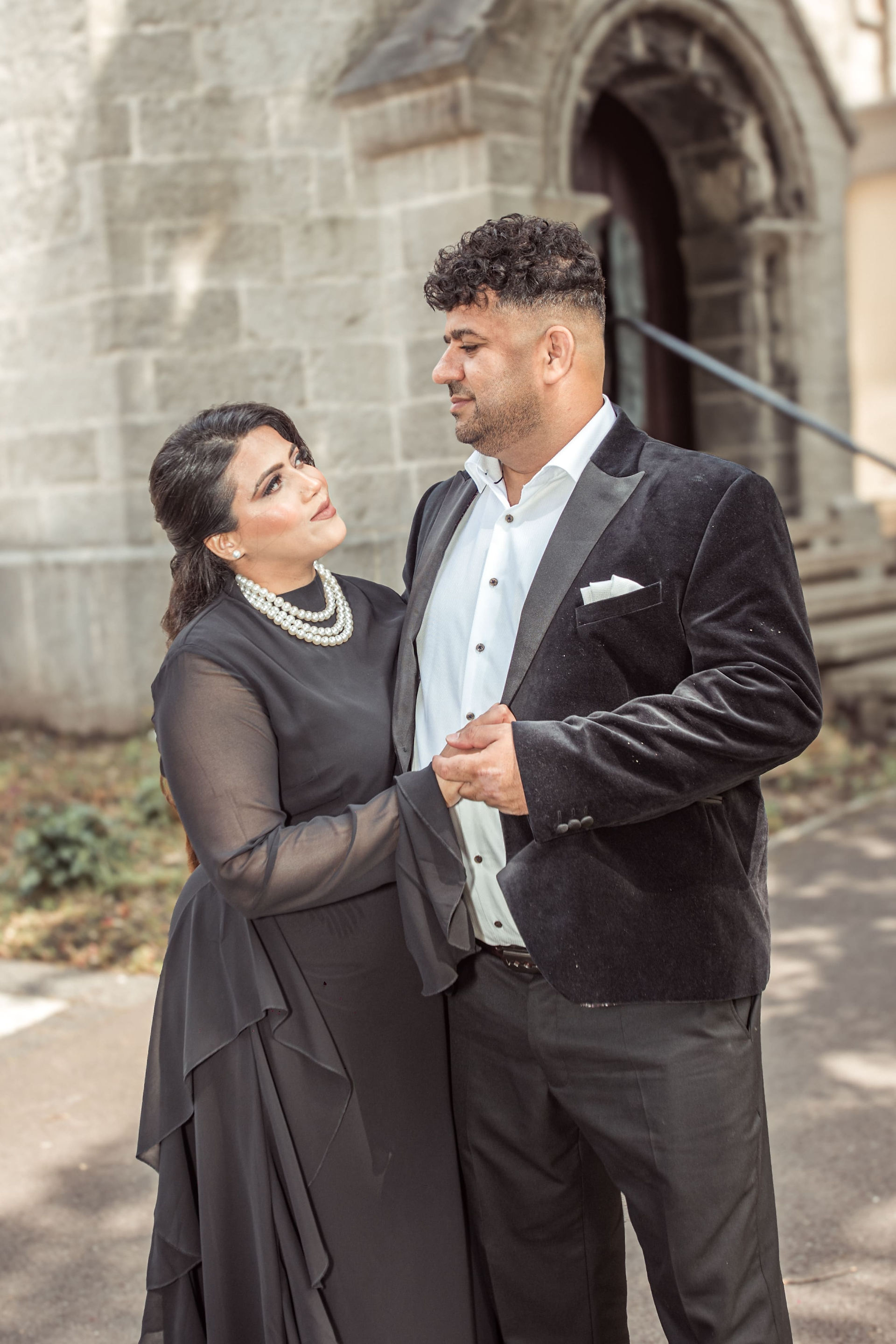Bride gazing lovingly at her groom while holding his hand, standing in front of the stone steps of the registry office.
