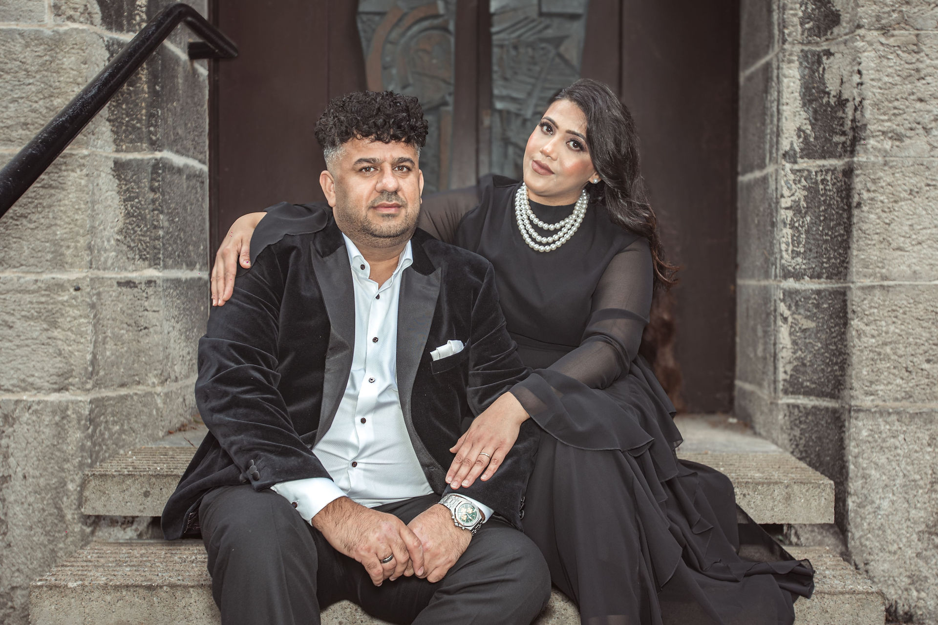 Bride and groom seated on the stone steps of Preston Registry Office, leaning into each other in a relaxed portrait.