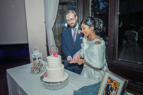 Bride and groom cutting their wedding cake at Walton Hall, smiling and sharing the moment.