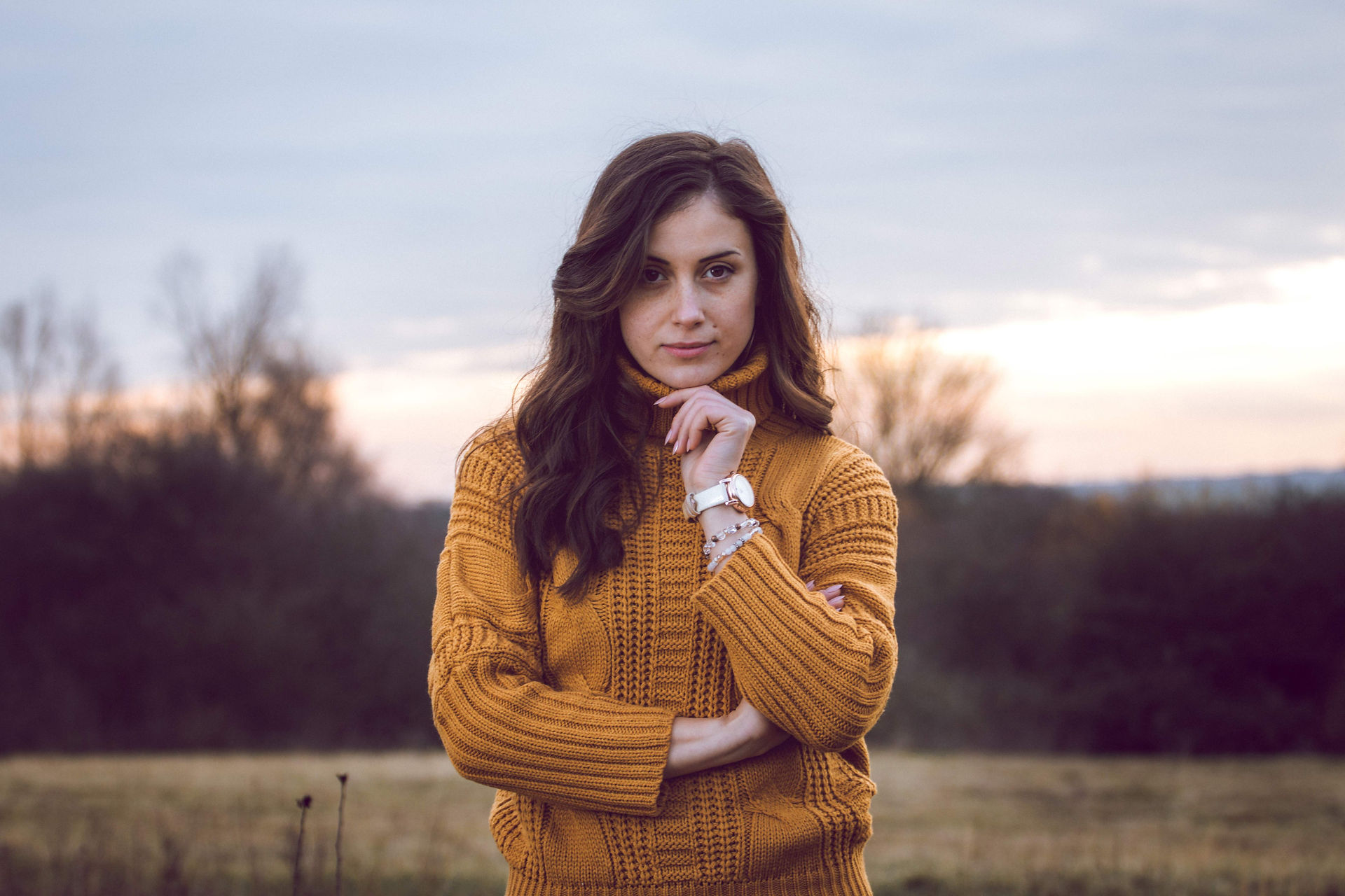 portrait of brunette woman smiling during golden hour wearing mustard sweater