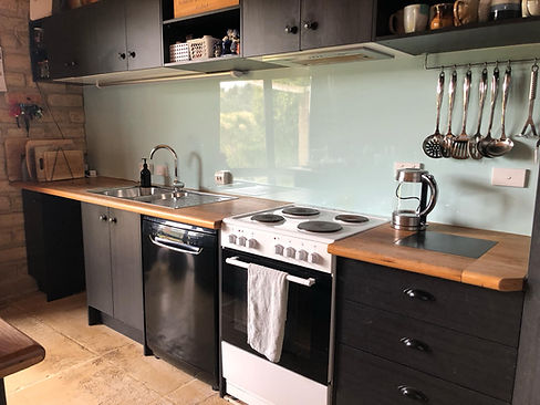 A stylish modern, high quality kitchen with soft close drawers and wall hung cupboards, custom wooden oak benchtop and quality backsplash / slashback.