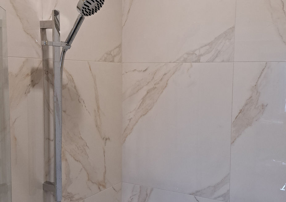 A tiled shower with glass shower door.