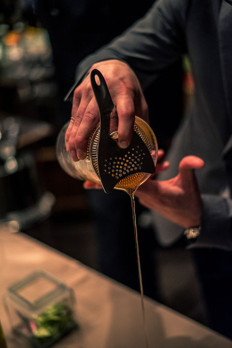 A photo of a bartender pouring a cocktail in a fine dining restaurant taken as part of a lifestyle event for food, beverage, and hospitality company run by celebrity Chef Wolfgang Puck. Taken by Philadelphia based photographer Joshua Dahl.