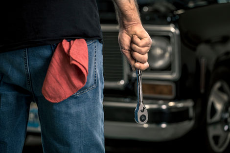 A photo of a mechanic holding a ratchet in front of a classic truck for a lifestyle industrial photoshoot. Taken by Philadelphia based photographer Joshua Dahl.
