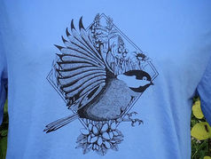 Custom design of a bird with a geometric and flower background on blue shirt. 