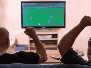 Two friends happily watching a Football match on TV
